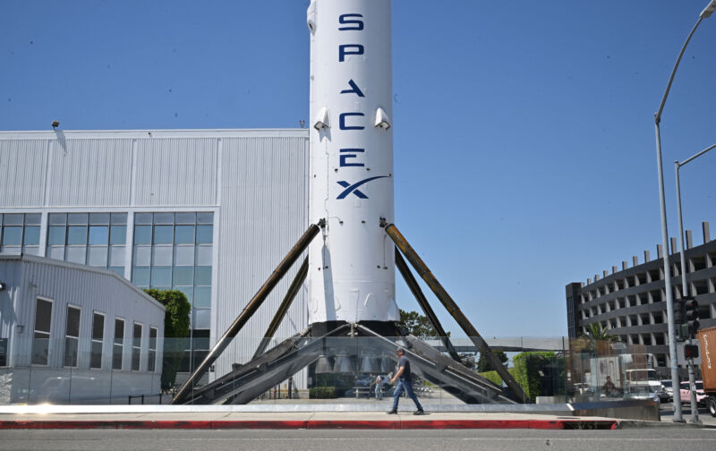 A pedestrian walks past a flown Falcon 9 booster at SpaceX headquarters in Hawthorne, California, on Tuesday, the same day Elon Musk said he will relocate the headquarters to Texas.